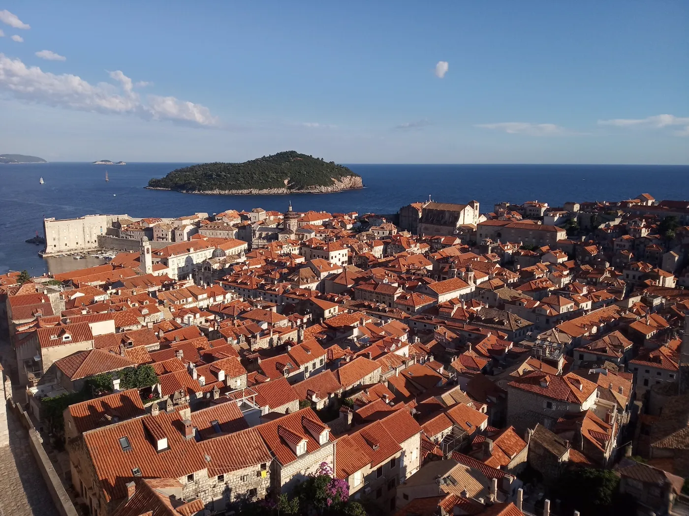 Red rooftops of Dubrovnik Old Town seen from the city walls, with Lokrum island behind